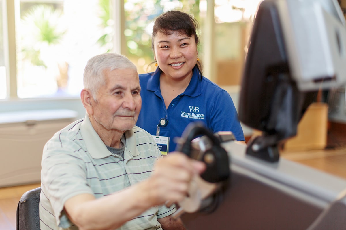 Therapist helping male elderly with exercise machine
